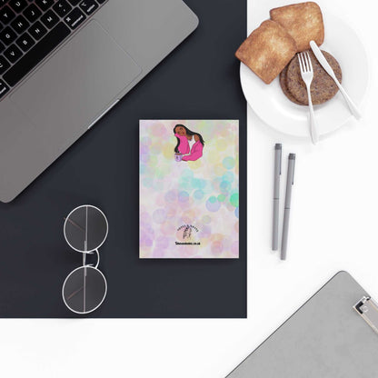 Branded A5 notebook with colorful hardback cover on a desk with laptop and snacks.