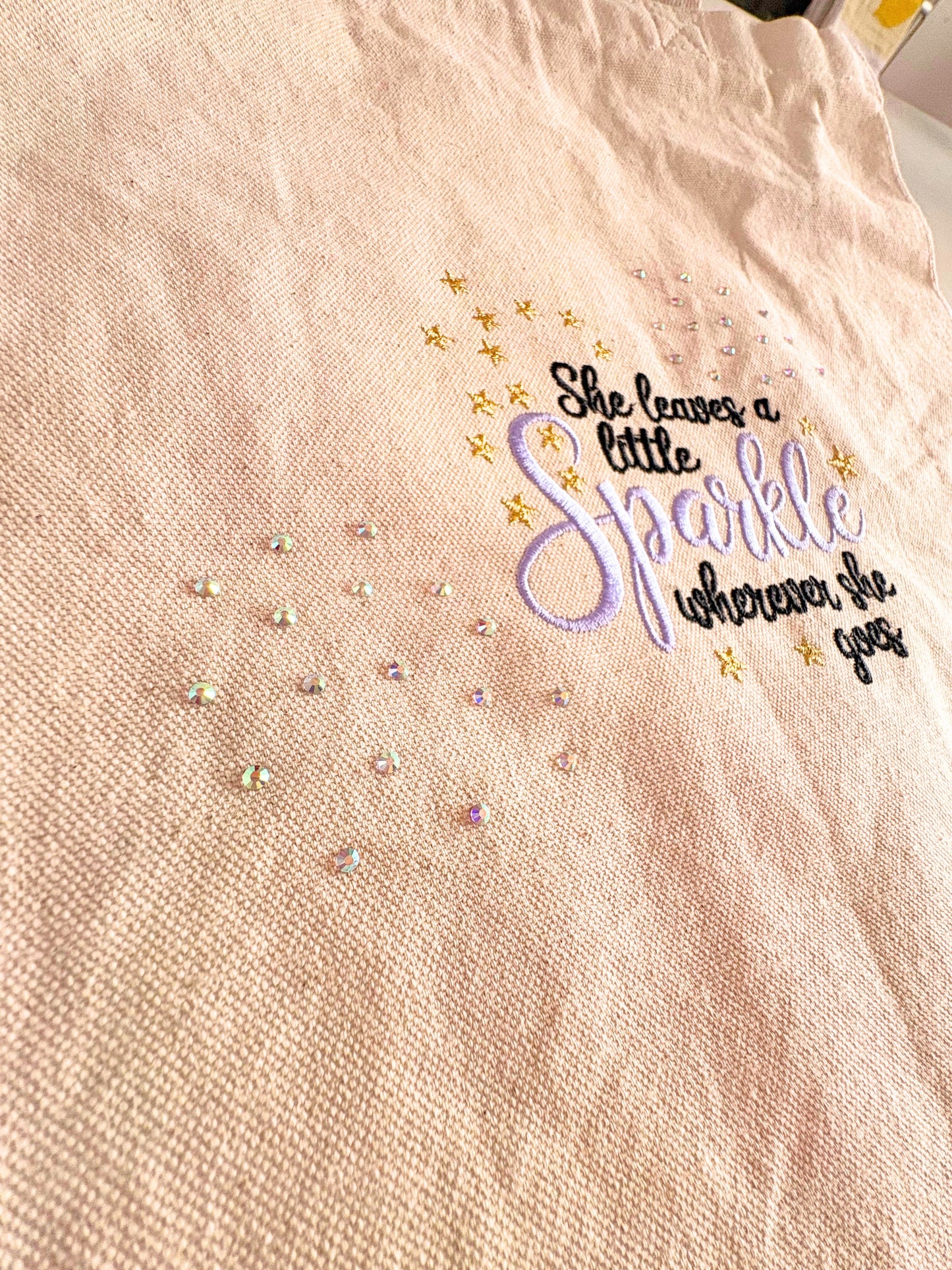 Embroidered canvas tote bag with "She Leaves a Little Sparkle Wherever She Goes" slogan and sparkling diamante details