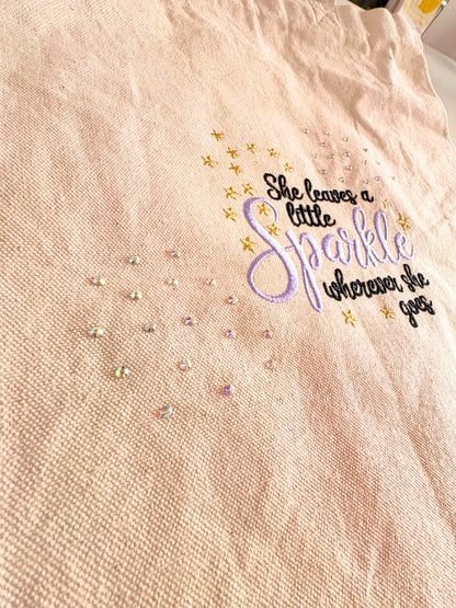 Embroidered canvas tote bag with "She Leaves a Little Sparkle Wherever She Goes" slogan and sparkling diamante details