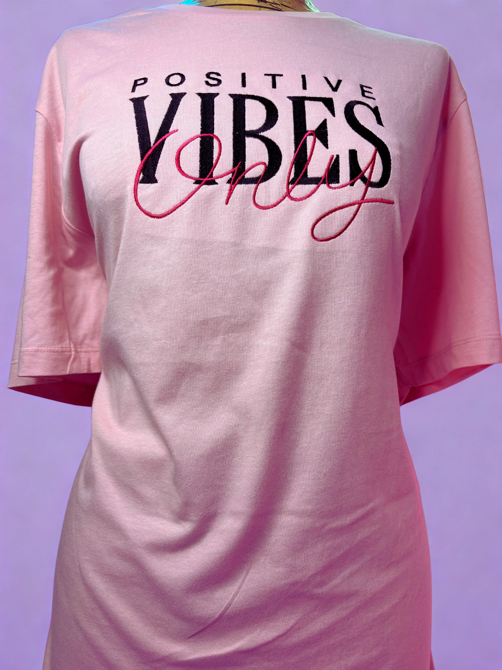 Baby pink short sleeve t-shirt with embroidered "Positive Vibes Only" text and ribbed crew neck