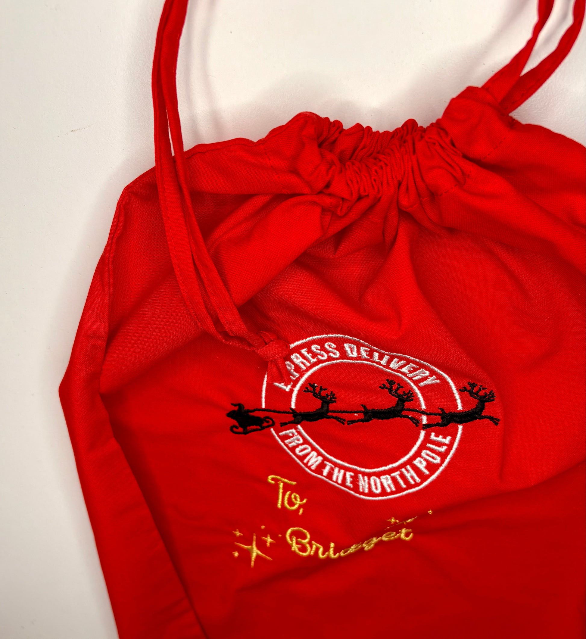 Red personalised Christmas drawstring sack with embroidered "Special Delivery from the North Pole" design and custom gold name embroidery