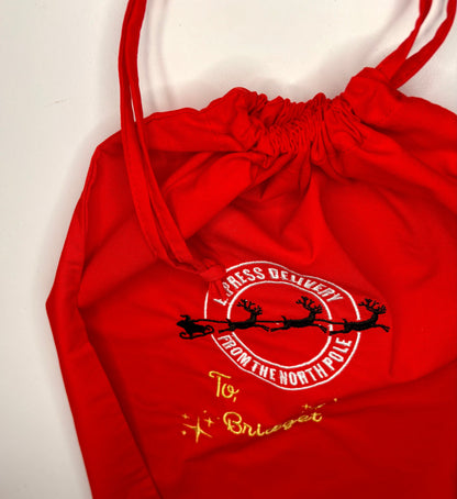 Red personalised Christmas drawstring sack with embroidered "Special Delivery from the North Pole" design and custom gold name embroidery