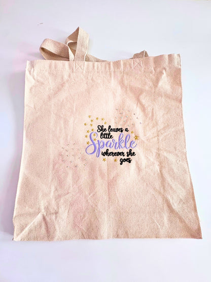 Embroidered canvas tote bag with "She Leaves a Little Sparkle Wherever She Goes" slogan and sparkling diamante embellishments