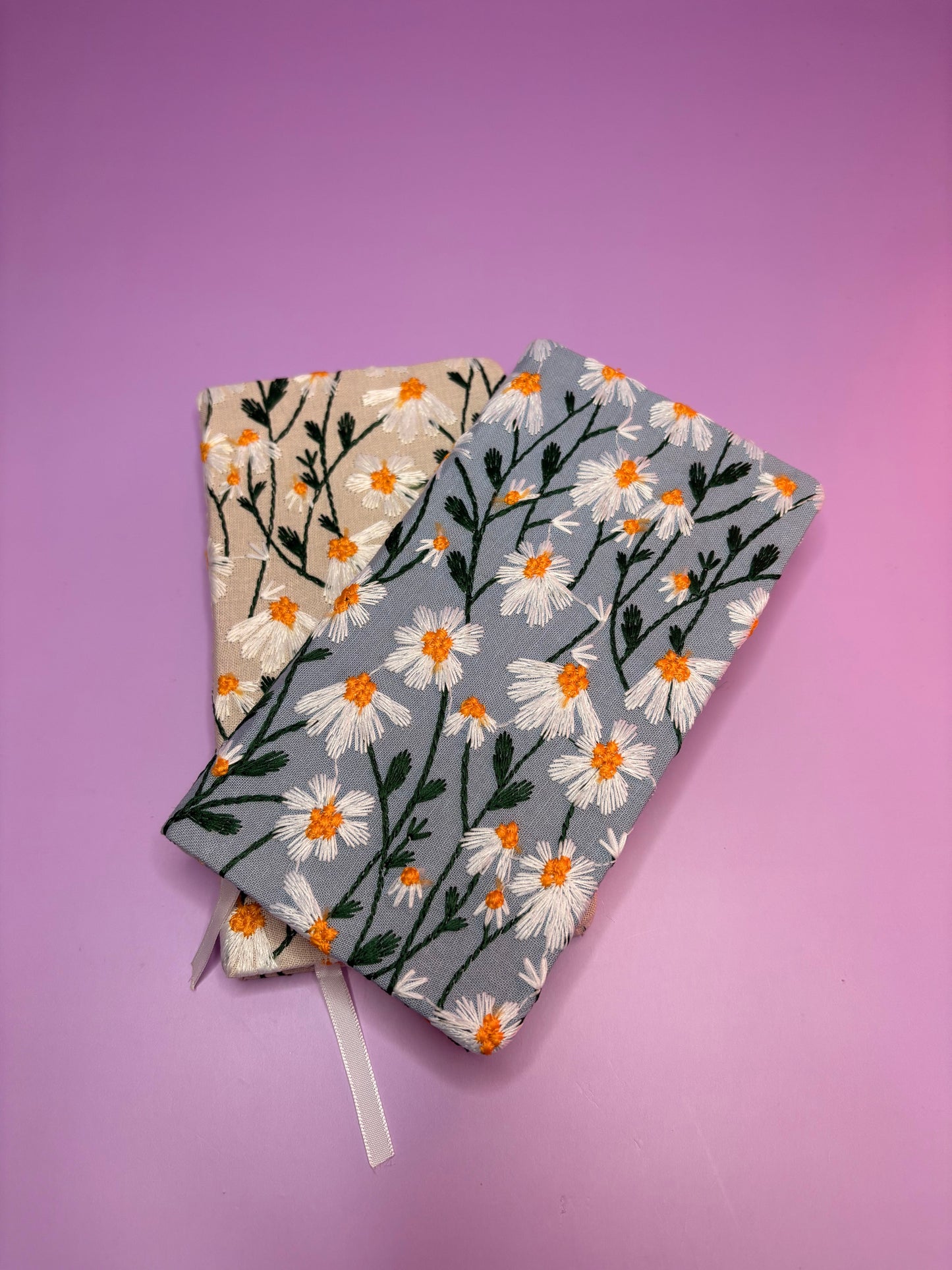A6 embroidered daisy notebooks with hardback covers in blue and cream on purple background