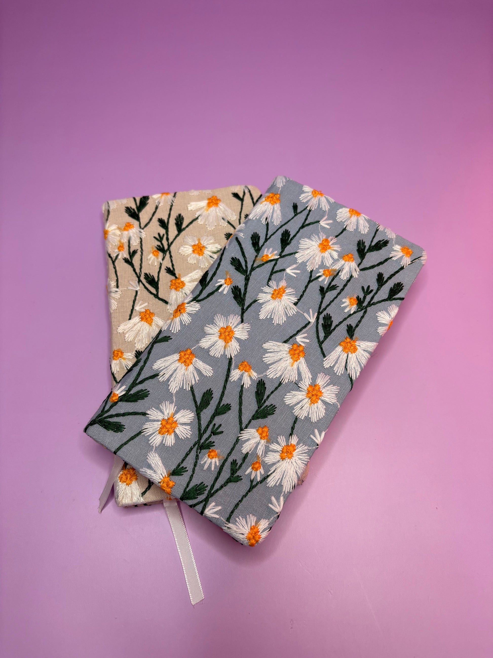 A6 embroidered daisy notebooks with hardback covers in blue and cream on purple background