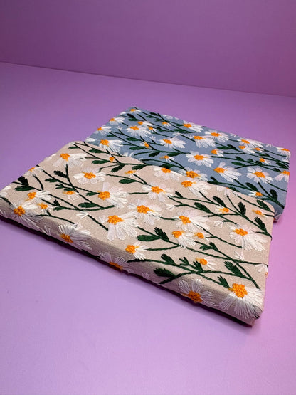 A6 embroidered daisy notebooks with blue and cream hardback covers on purple background