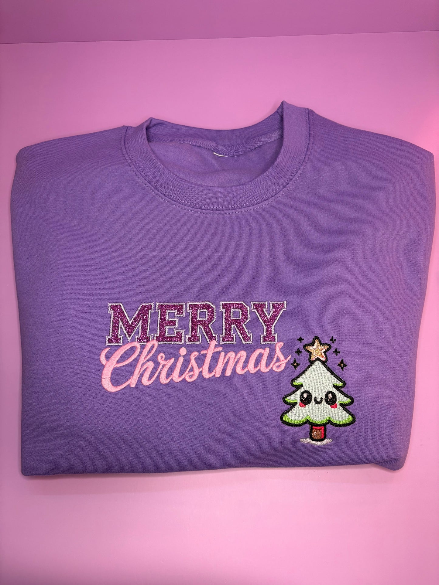 Lilac kawaii style glitter Merry Christmas jumper folded on pink background Christmas Jumper