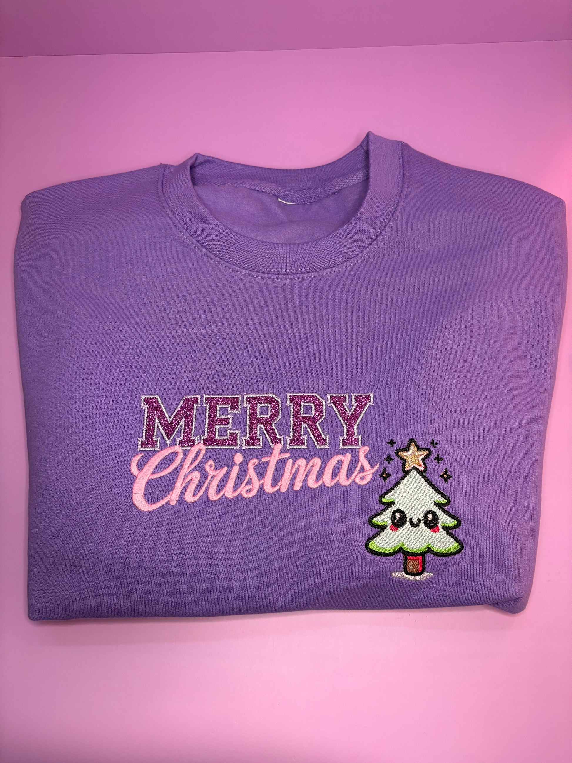 Lilac kawaii style glitter Merry Christmas jumper folded on pink background Christmas Jumper