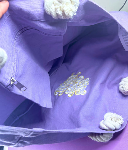 Lilac marine style tote bag interior with internal zip pocket and gold embroidered "Enjoy Every Moment" message, featuring thick twisted rope handles.