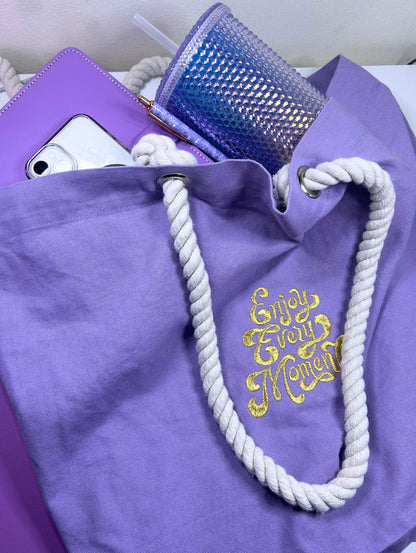 Lilac marine style tote bag with white twisted rope handles and gold "Enjoy Every Moment" embroidery
