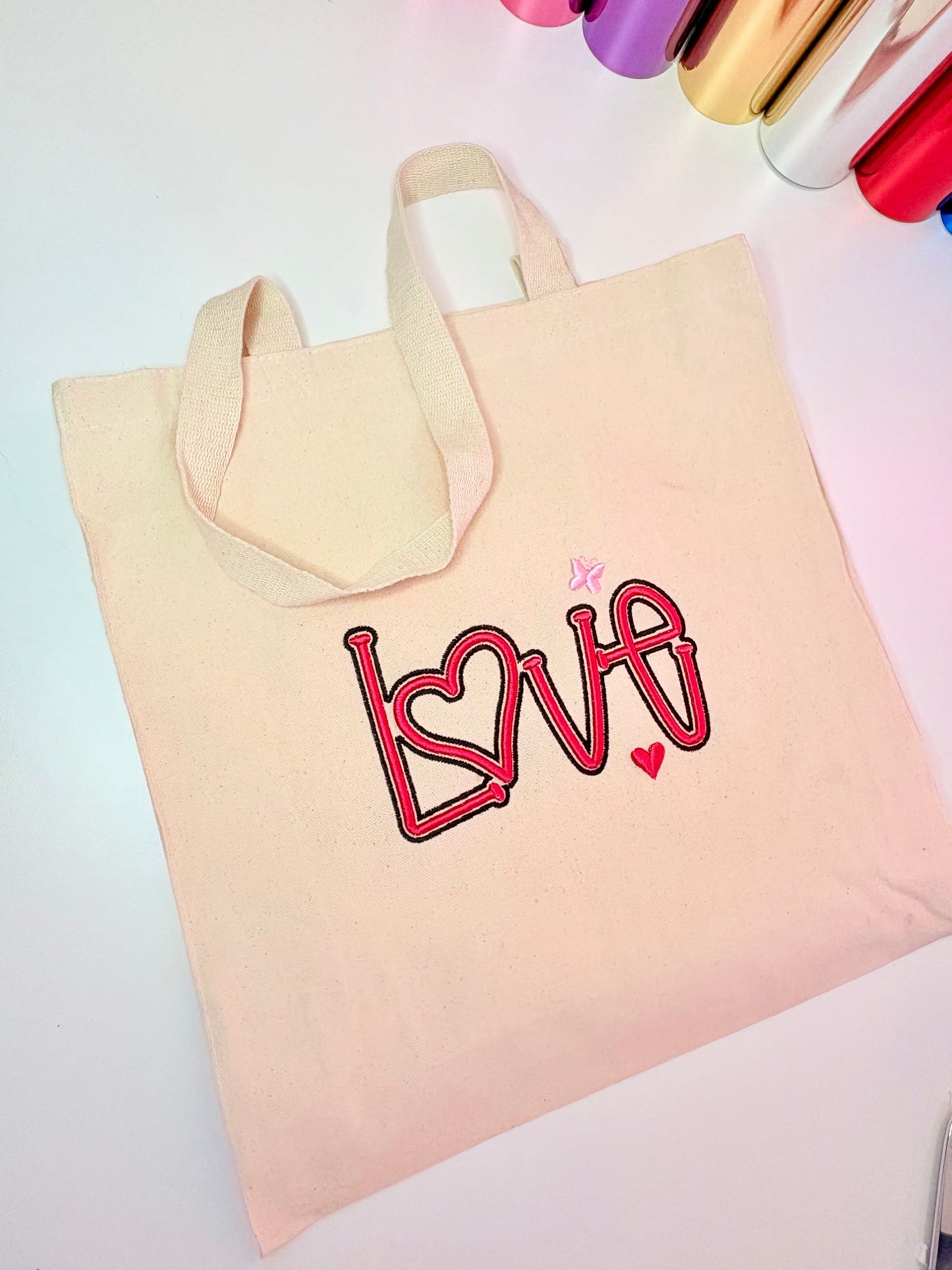 Heavy canvas tote bag with 3D puff embroidered LOVE design and long handles, 24L capacity, beige color.