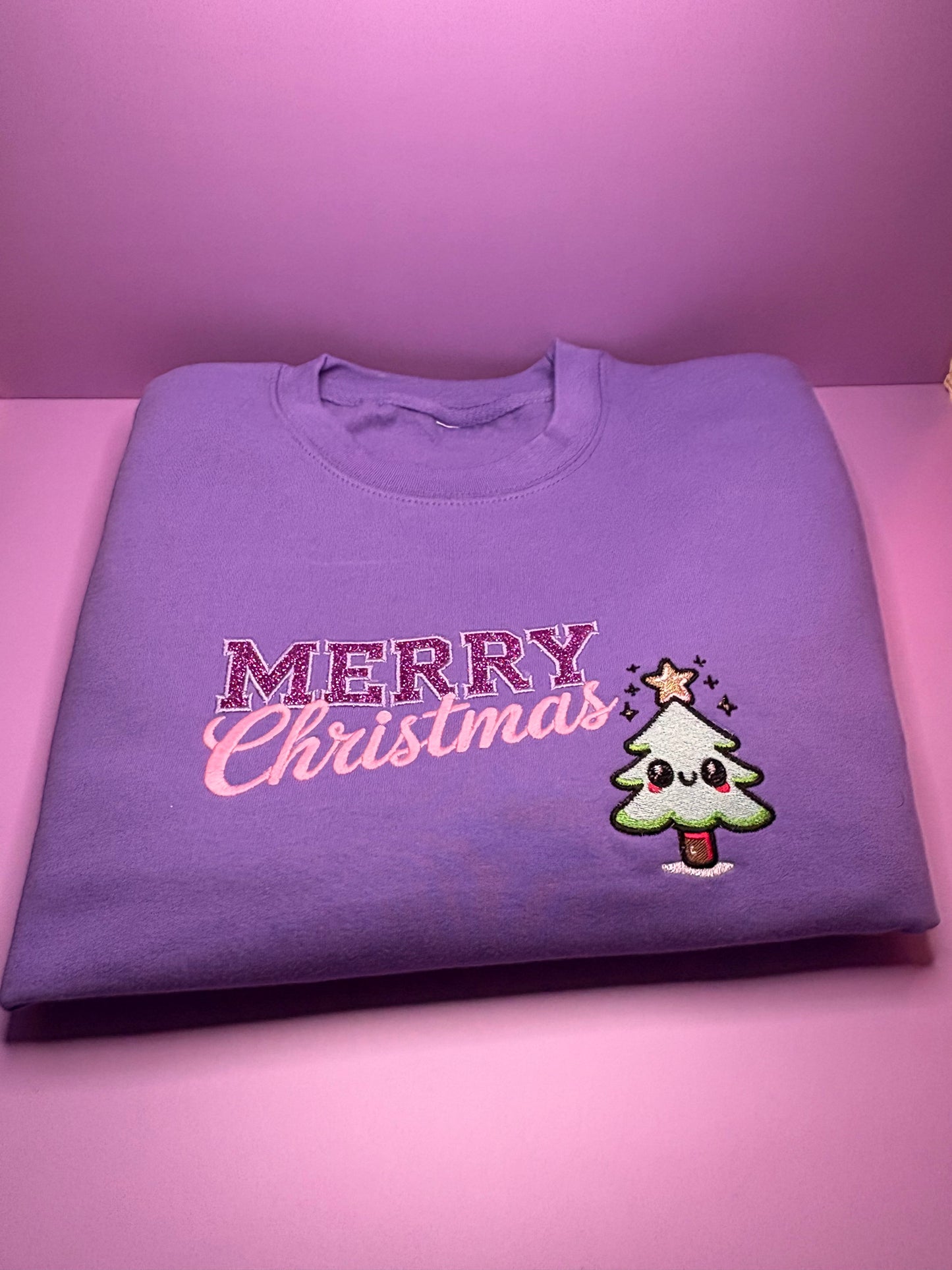 Lilac glitter kawaii Merry Christmas jumper folded on pink background Christmas Jumper