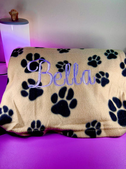 Personalised fleece dog blanket with paw prints and embroidered name.