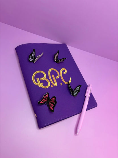 Purple A5 fabric file with personalized 3D butterfly lace embroidery and pink pen on pink surface