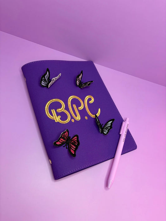Purple A5 fabric file with personalized 3D butterfly lace embroidery and pink pen on pink surface