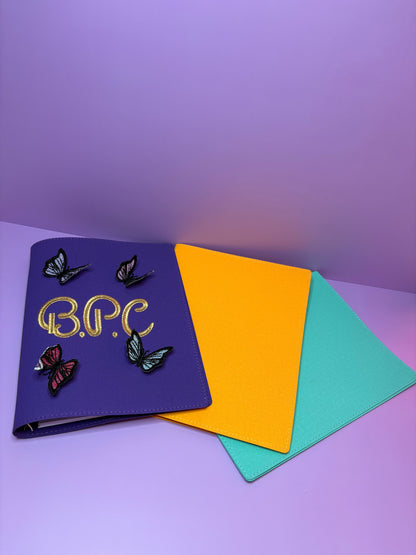 3D butterfly embroidered personalised A5 fabric file notebook in purple with yellow and aqua covers displayed on a purple background