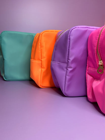 Set of colourful personalised 3D puff embroidered large cosmetic bags in mint, orange, lilac, and pink colors against purple background