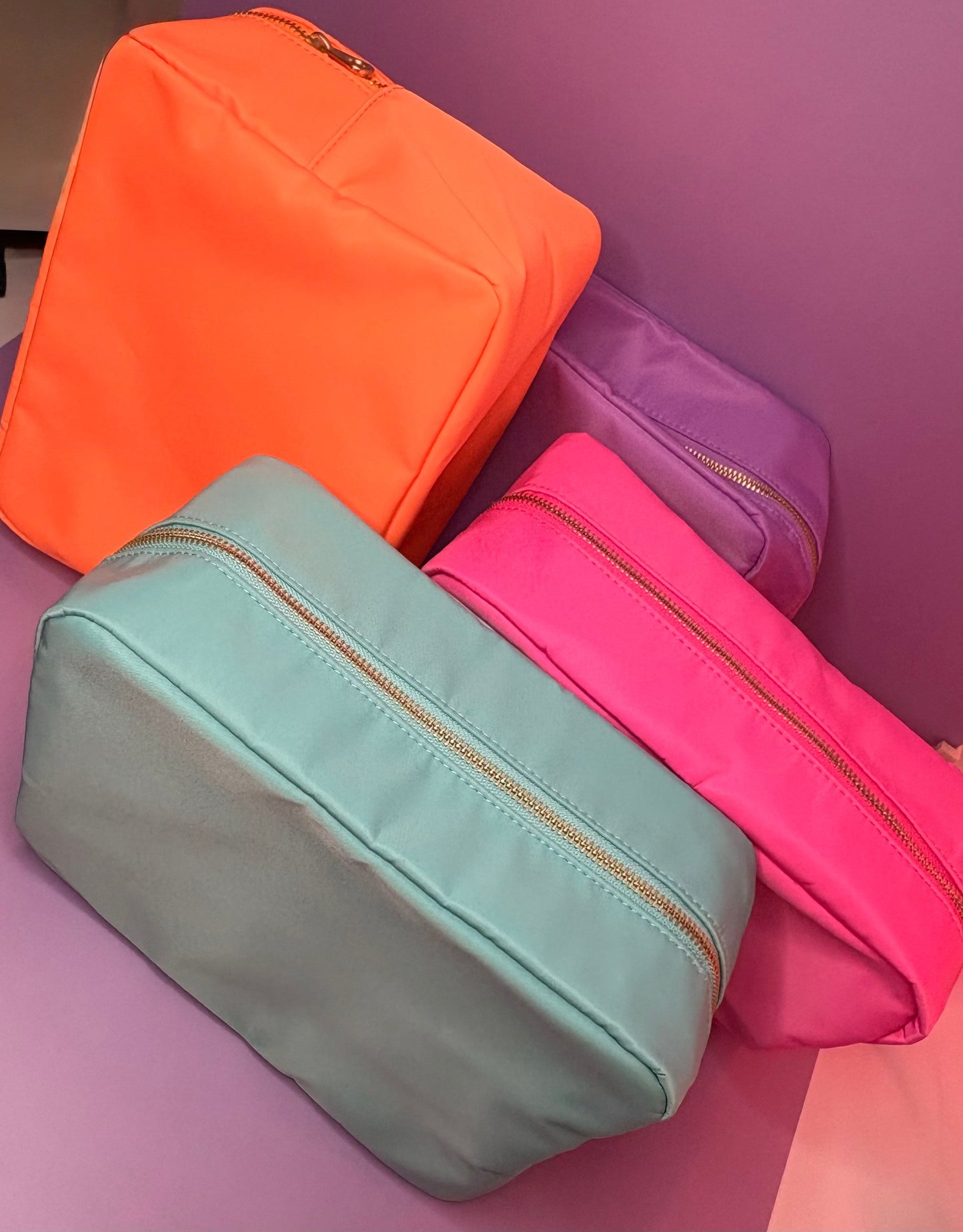 Set of four large personalised 3D puff embroidered cosmetic bags in orange, lilac, pink, and mint colors.