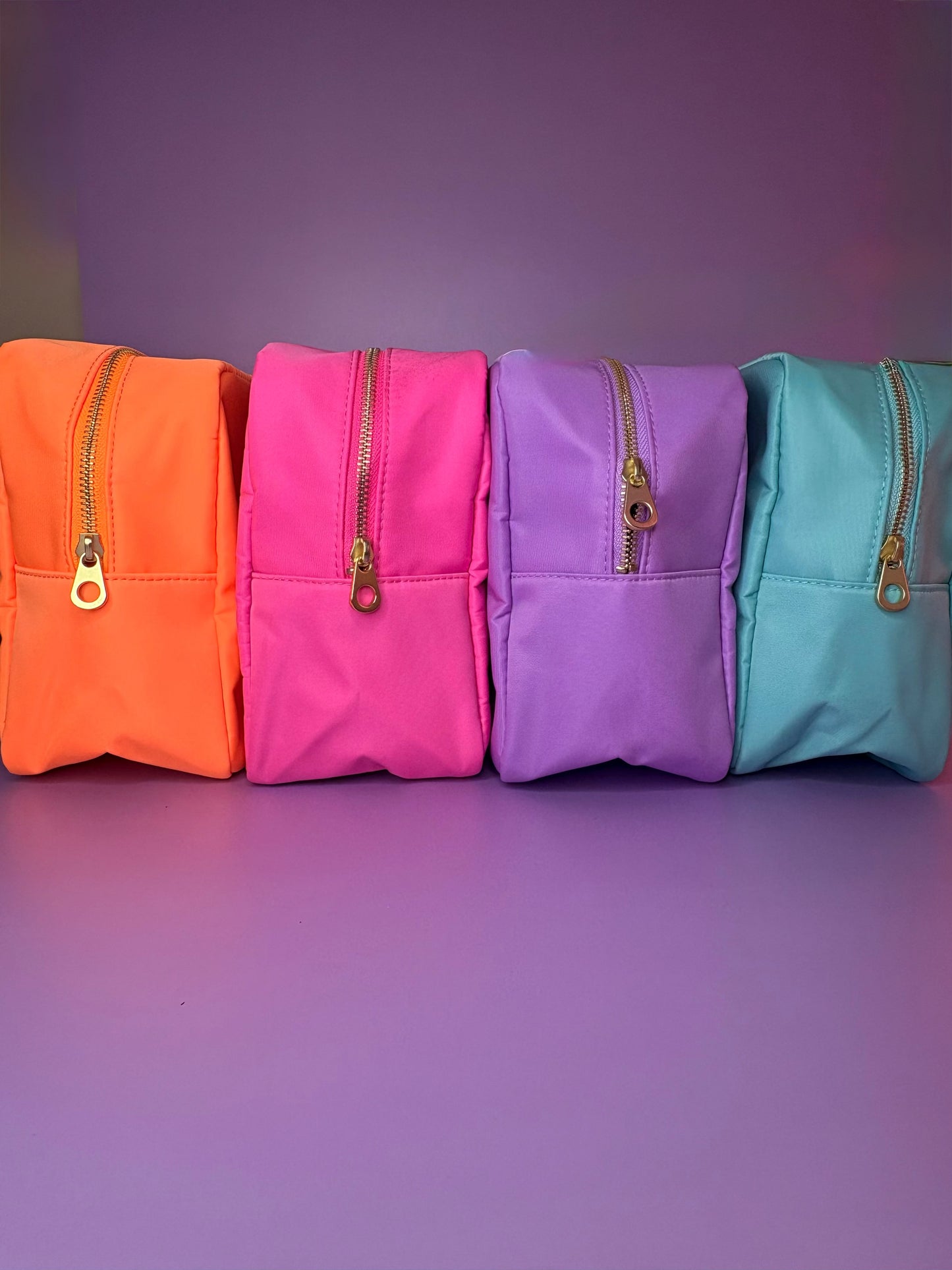 Row of colourful large personalised 3D puff embroidered cosmetic bags in orange, pink, purple, and mint colors