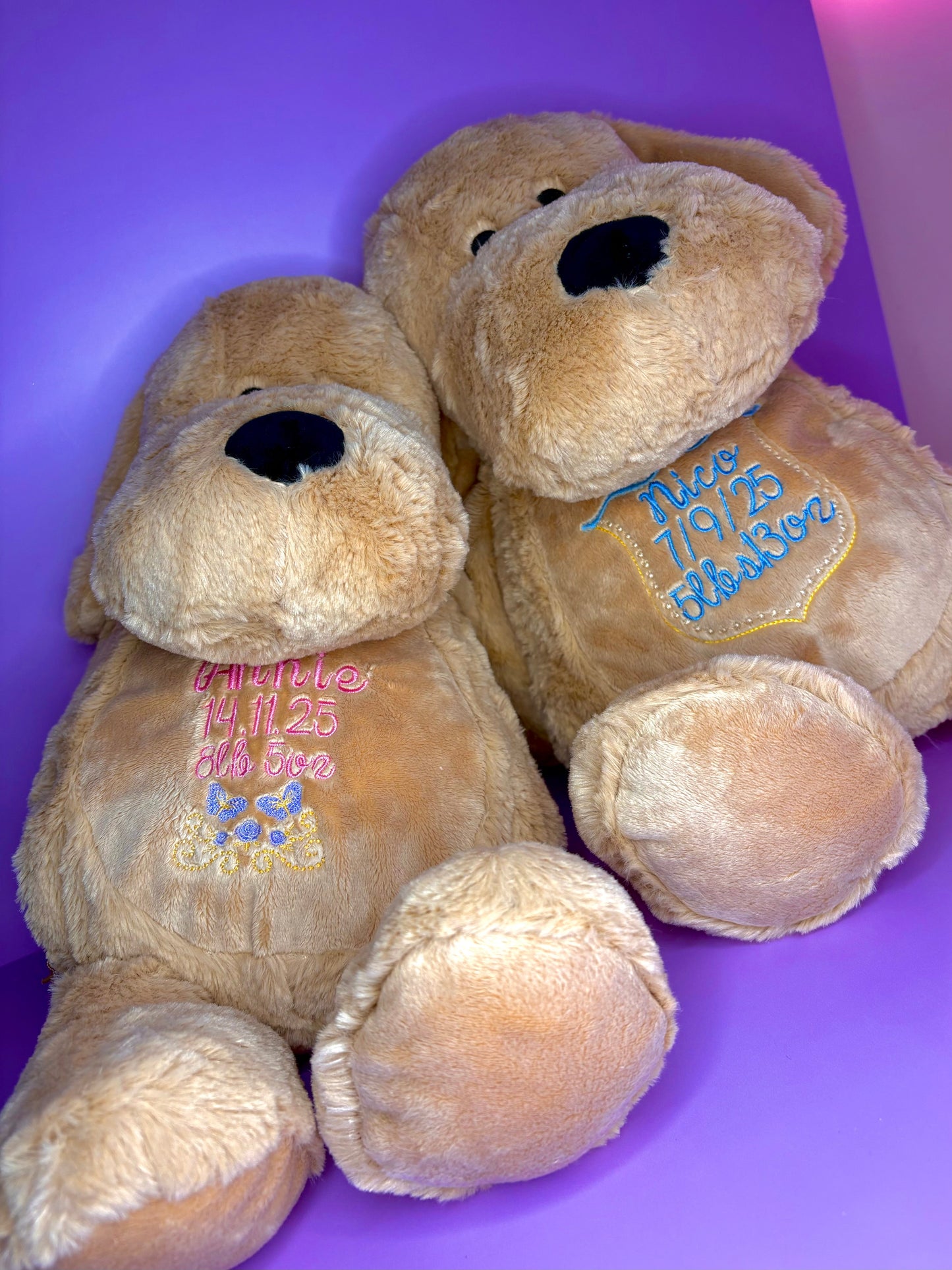 Two personalised birth announcement soft toy dogs with embroidered birth details on soft plush fabric