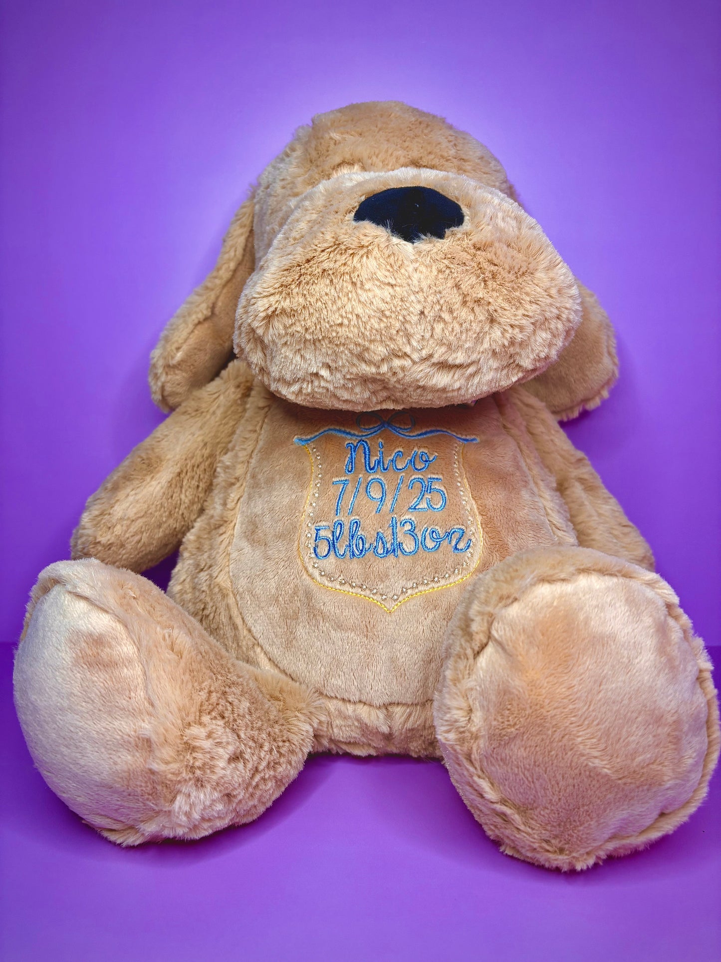 Personalised birth announcement soft toy dog with embroidered baby details on purple background