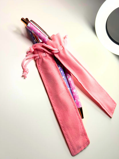 Kawaii Luxe Metal Ballpoint Pens in pink and purple with velvet pouches on a white surface