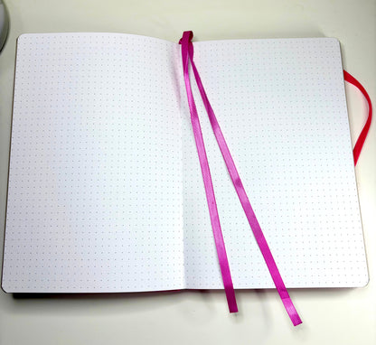 Open Tiny Spells Notebook showing dotted pages and pink ribbon bookmarks