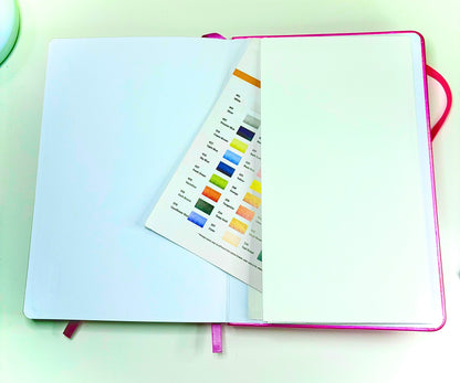 Open Tiny Spells Notebook showing blank pages and color chart with pink ribbon markers and back pocket
