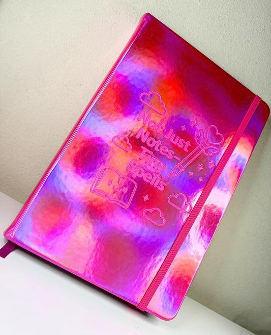 A5 holographic Tiny Spells Notebook with pink elastic band and embossed cover design