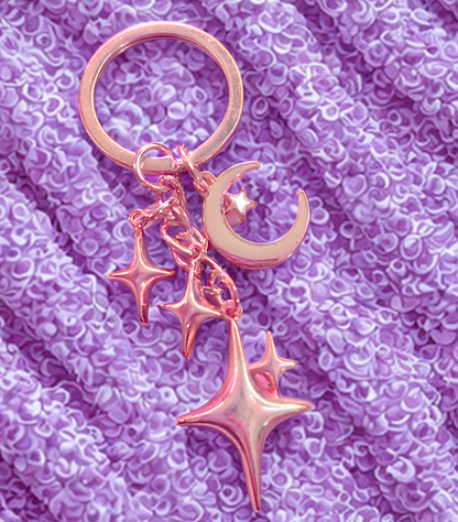 3D metal alloy gold starry night moon and stars keychain on purple fabric background
