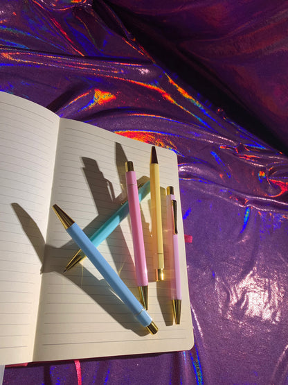 Pastel paradise pen set with hexagonal barrels, gold trim, blue ink, and colorful pastel design on a shiny surface.